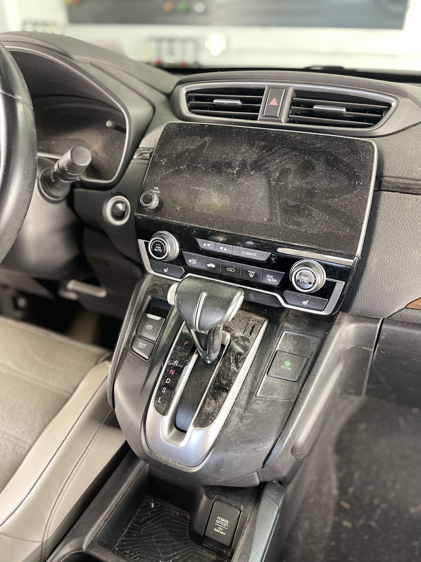 Honda CR-V center console and screen covered in dust before detailing