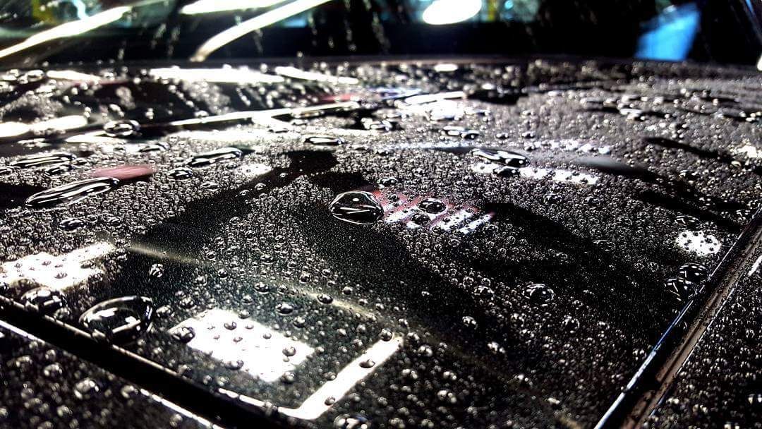 Water beading into tight droplets on a ceramic-coated black hood