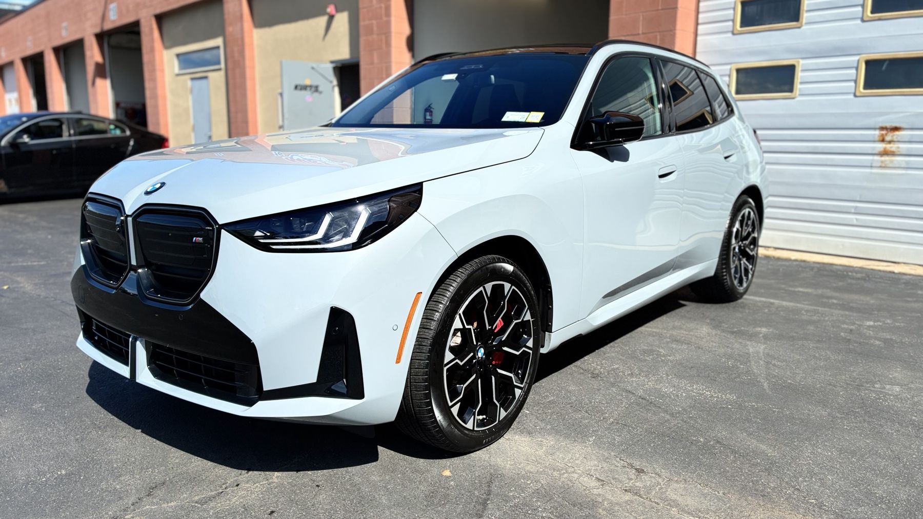 White BMW SUV with a clean, high-gloss finish outside the shop