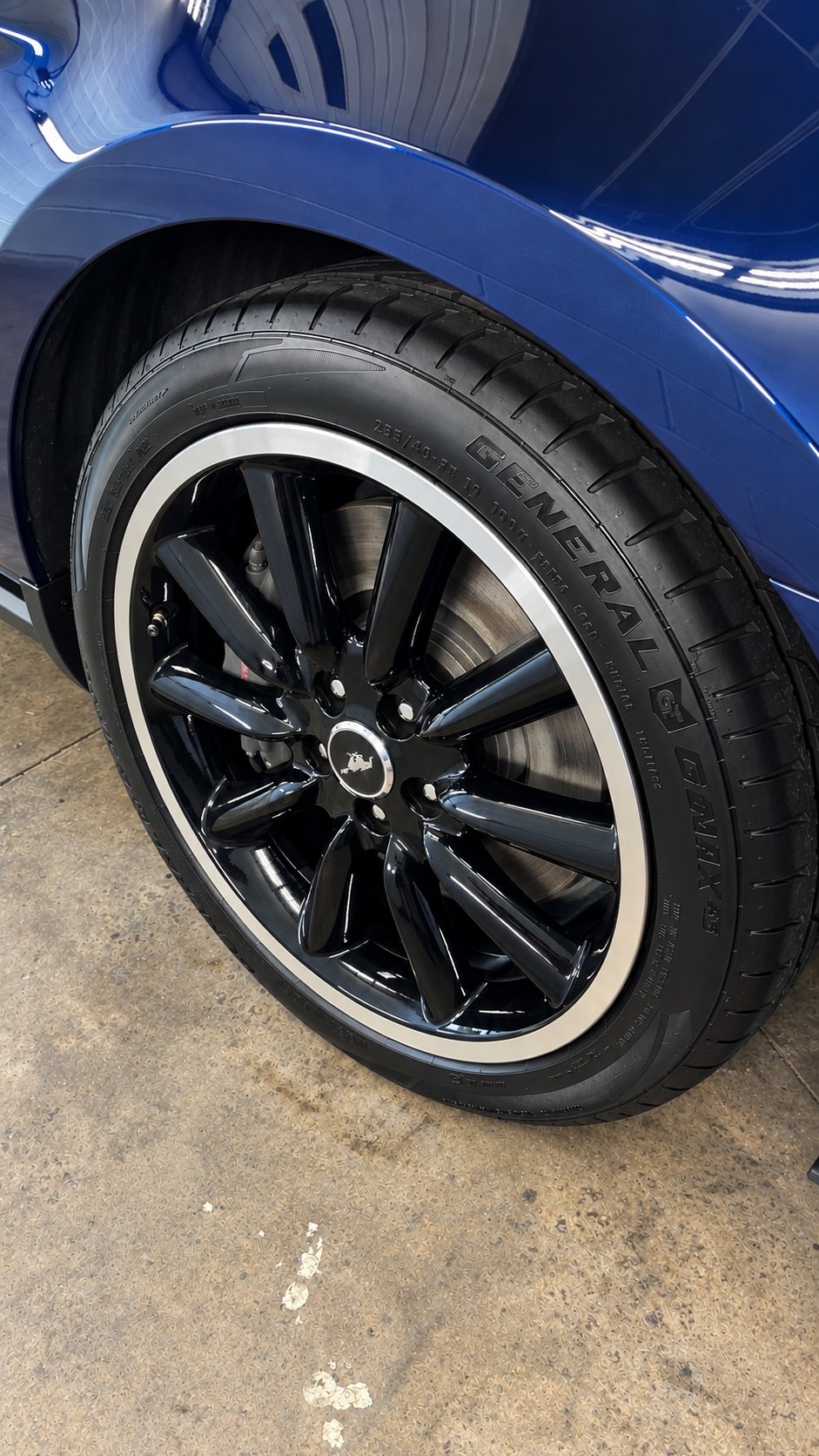 The same Mustang wheel clean and glossy with a dressed tire after detailing