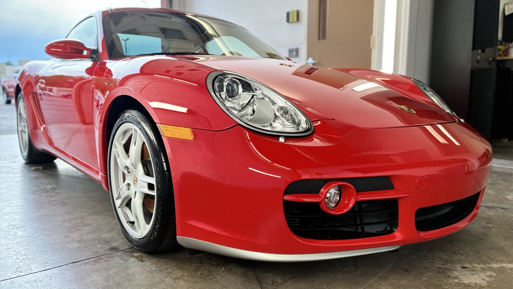 Red Porsche Cayman with deep, glossy paint inside the shop